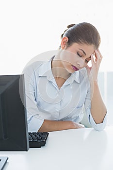 Businesswoman suffering from headache in front of computer