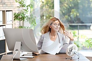 Businesswoman suffering from heat in front of small fan