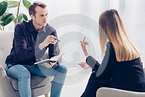 Businesswoman in suit giving interview to handsome journalist in casual shirt