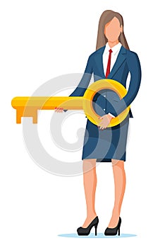 Businesswoman in suit holding big golden key.