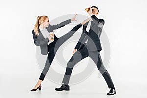 businesswoman in suit kicking businessman with coffee to go