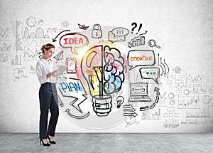 Businesswoman with tablet, colourful light bulb with brain, doodle icons