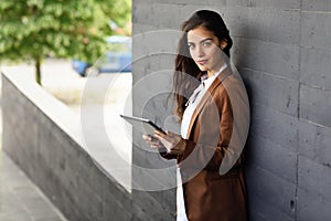 Businesswoman with tablet computer standing outside of an office