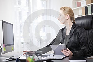 Businesswoman with Tablet Using a Desktop Computer