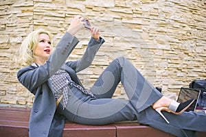 Businesswoman taking selfies. A woman on a bench makes a video call