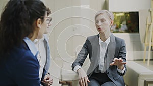 Businesswoman talking and duscussing future contract with business partners sitting on couch in modern office center