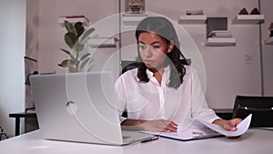 Businesswoman talking in front of laptop and looking at resume at table in company spbi.