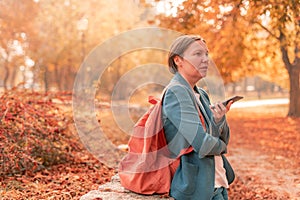 Businesswoman talking on mobile phone in autumn park