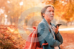 Businesswoman talking on mobile phone in autumn park