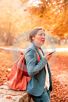 Businesswoman talking on mobile phone in autumn park