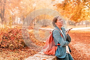 Businesswoman talking on mobile phone in autumn park