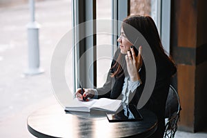 businesswoman talking on the phone and taking notes