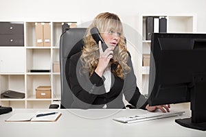 Businesswoman talking on the phone while typing