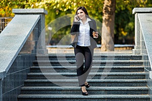 Businesswoman talking on phone while walking outdoor