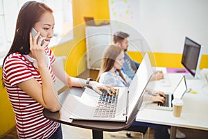 Businesswoman talking on phone while working in creative office