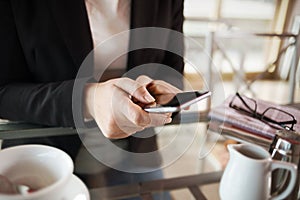 Businesswoman texting with her mobile during a coffee break