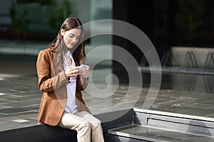 Businesswoman texting with a smartphone next to an office building