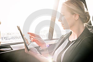 Businesswoman touching digital tablet screen in car