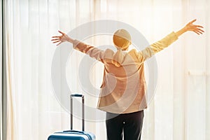 Businesswoman traveller standing in hotel room by window feeling happy