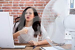 Businesswoman Try To Cool Herself By Fan At Workplace