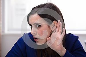 Businesswoman Trying To Hear With Hand Over Ear