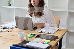 Businesswoman typing on laptop at workplace. Woman working in ho