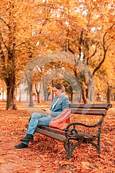 Businesswoman typing text message on mobile phone on park bench