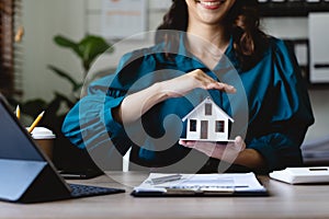 Businesswoman use their hands to protect the red roofs, the concept of protecting houses using the gestures and symbols