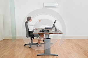 Businesswoman Using Air Conditioner In Office