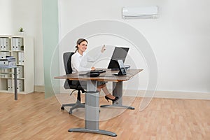 Businesswoman Using Air Conditioner In Office