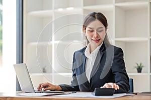 businesswoman using calculator for do math finance on wooden desk in office and business working background, tax