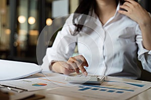 Businesswoman using a calculator to calculate numbers on a company& x27;s financial documents, she is analyzing