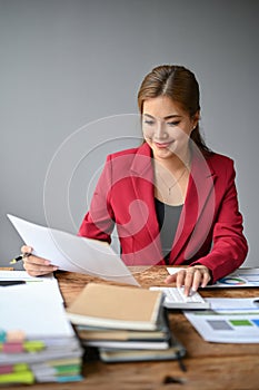 A businesswoman using a calculator to plan budgets and working on financial reports at her desk