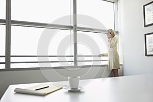 Businesswoman Using Cellphone By Office Window