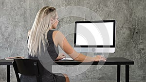 Businesswoman using desktop computer in creative office. White Display.