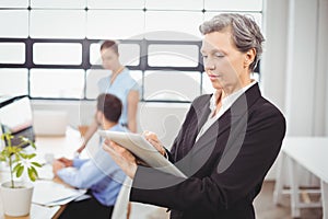 Businesswoman using digital tablet while colleagues in background