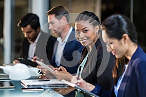 Businesswoman using digital tablet while colleagues writing notes