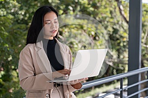 A businesswoman using her laptop, responding to an urgent email via her laptop on a skywalk