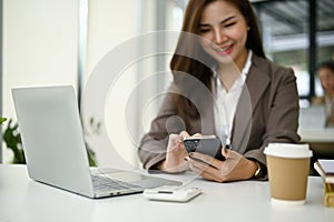 A businesswoman using her smartphone at her desk