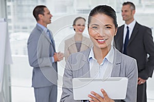 Businesswoman using her tablet pc while colleagues talking together