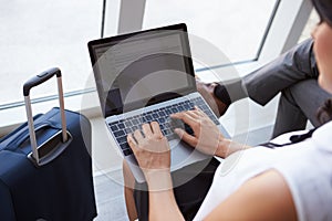 Businesswoman Using Laptop In Airport Departure Lounge photo