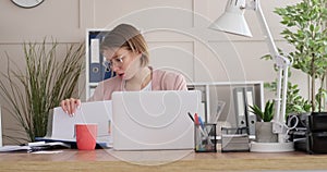 Businesswoman using laptop and checking filed documents