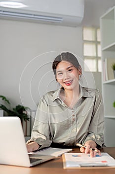 Businesswoman using laptop computer and calculator working at home with calculator document on desk, finance analysis