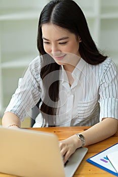 Businesswoman using laptop computer, looking at screen, typing