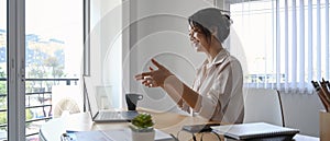 Businesswoman using laptop computer making video conference with her business partner at her workplace.