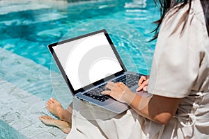 Businesswoman using laptop working remotely near swimming pool. Asian traveler woman working on computer during her summer holiday