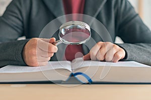 Businesswoman using magnifying glass to read the book