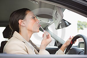 Businesswoman using mirror to put on lip gloss photo