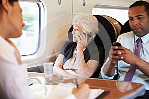 Businesswoman Using Mobile Phone On Busy Commuter Train