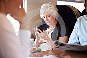 Businesswoman Using Mobile Phone On Busy Commuter Train photo